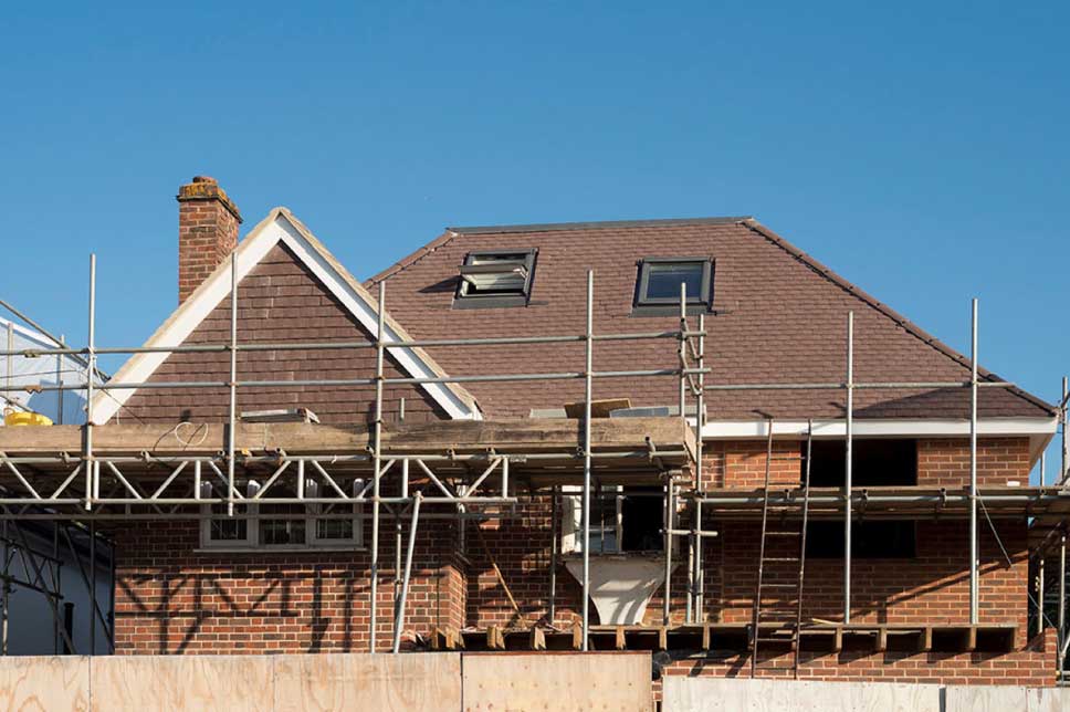 A house with scaffolding around it on a sunny day.